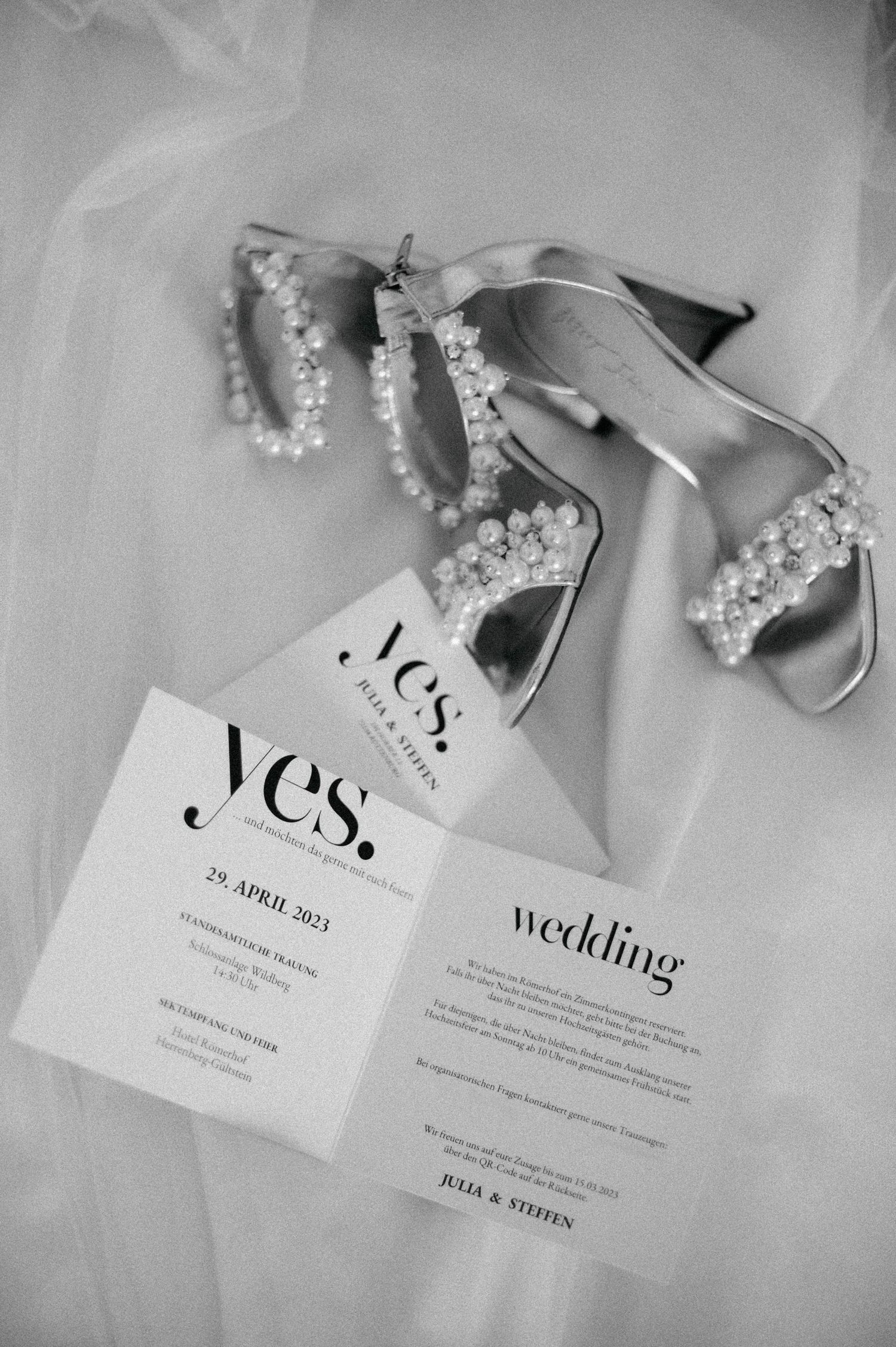 Elegant black and white wedding invitations with 'Yes' text and floral details arranged on a light surface.