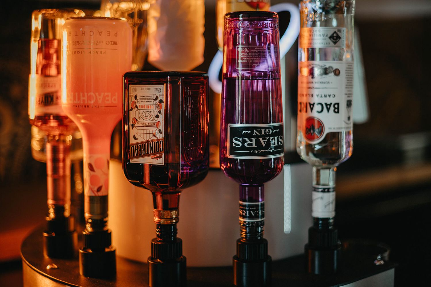 Backlit liquor bottles on a bar shelf create a warm amber glow through the glass containers.