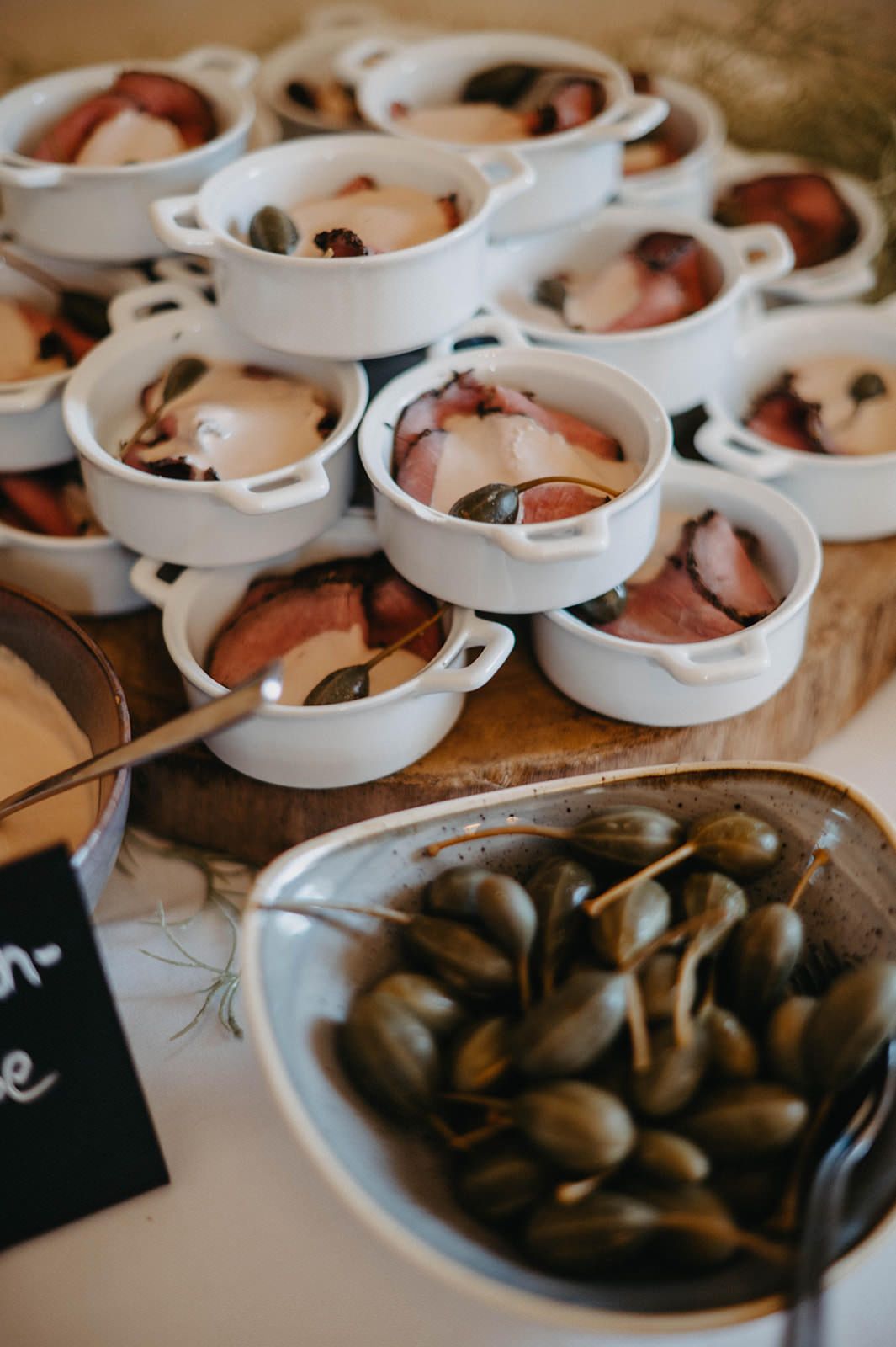 Several white ceramic ramekins filled with chocolate desserts sit alongside scattered coffee beans on a dark surface.