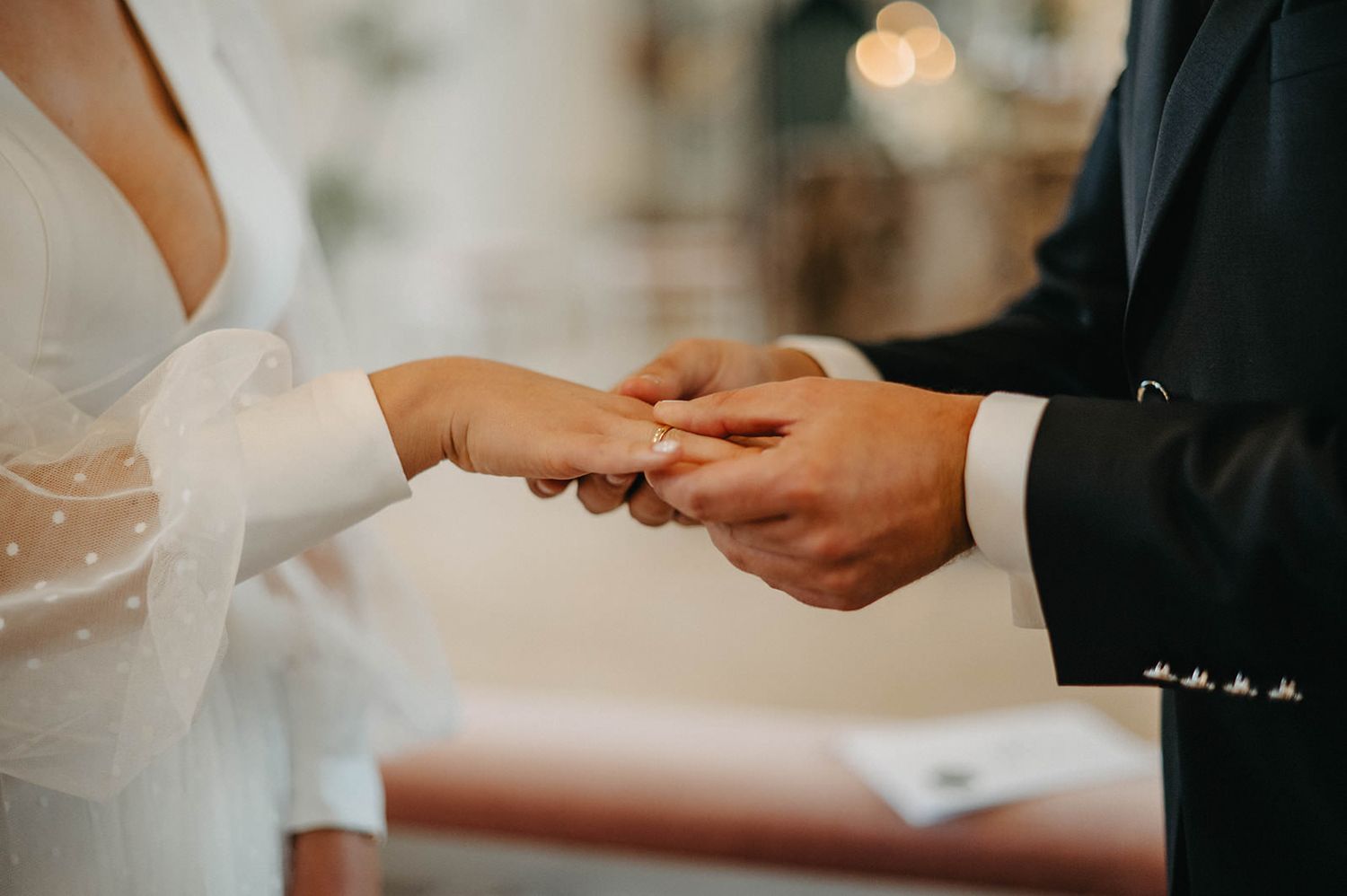Close-up shot of hands exchanging wedding rings during a romantic ceremony.