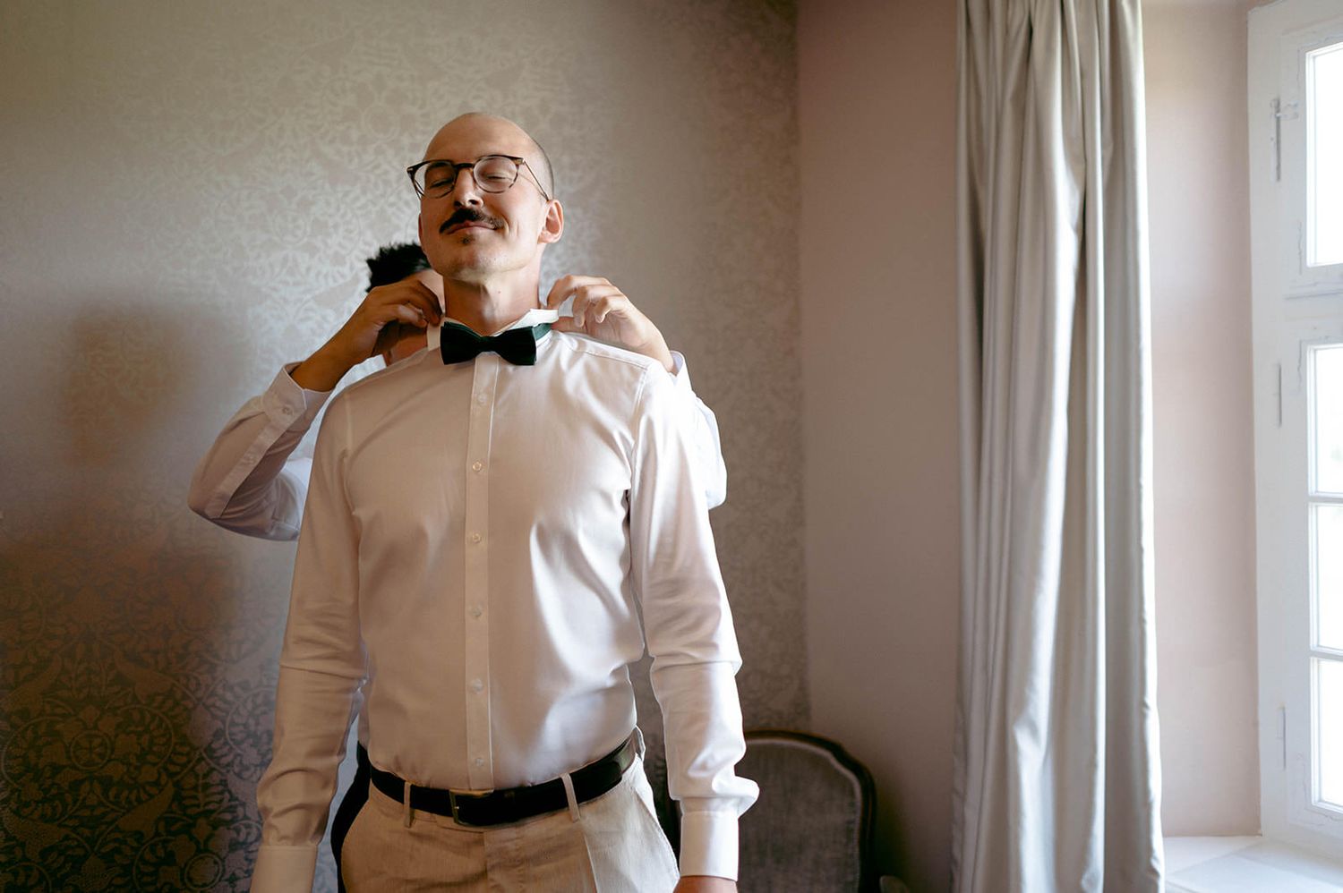 A sequence of black and white photos showing a person in a white shirt adjusting their tie in front of a window.