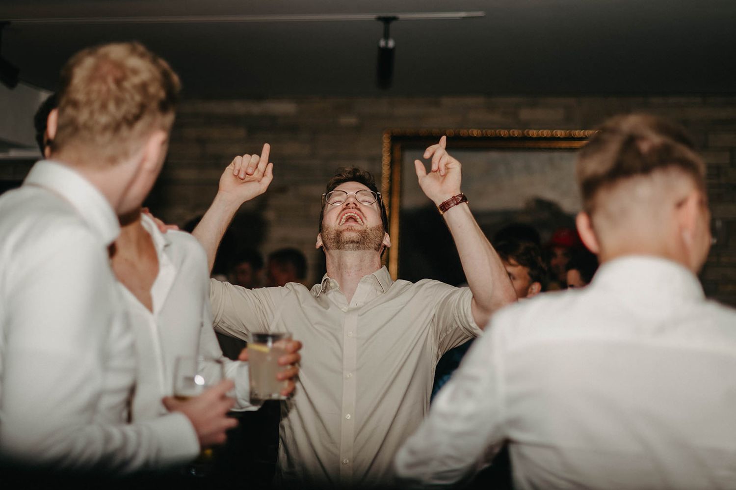 People dancing and celebrating at a lively party or reception with their arms raised in joyful movement.