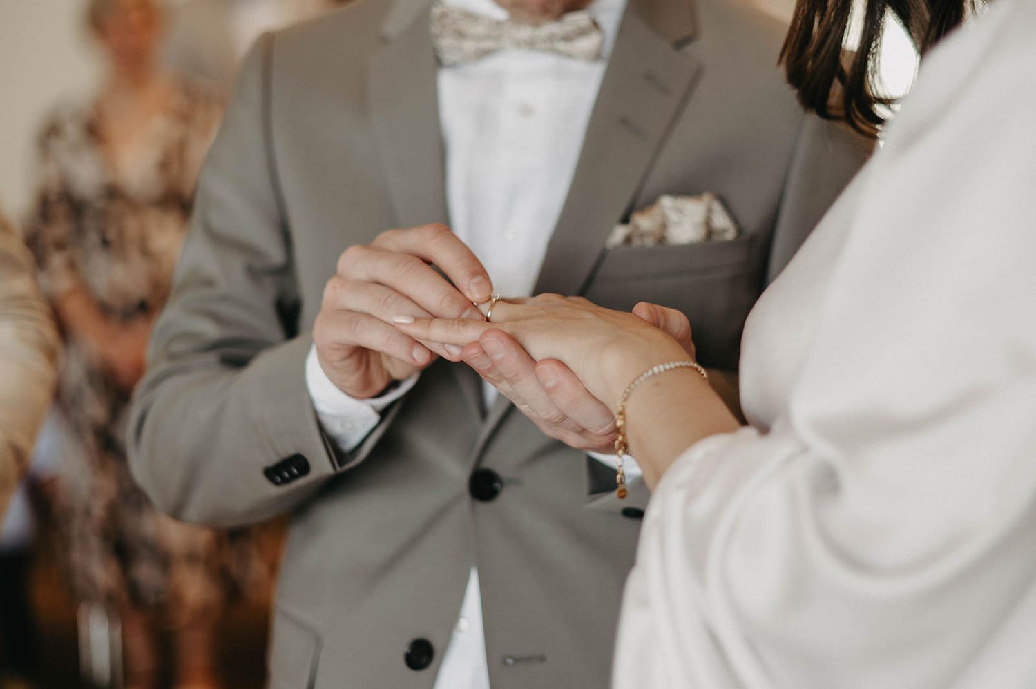 Close-up shot of hands exchanging wedding rings during a ceremony.