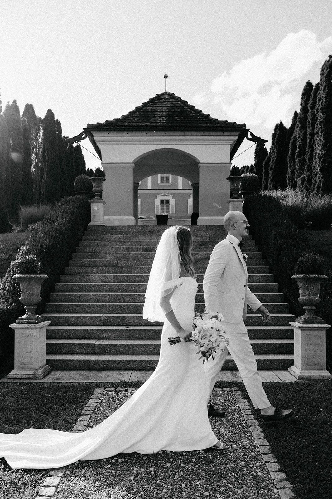 A series of black and white wedding photos showing a couple walking up stone garden steps with a flowing white dress.