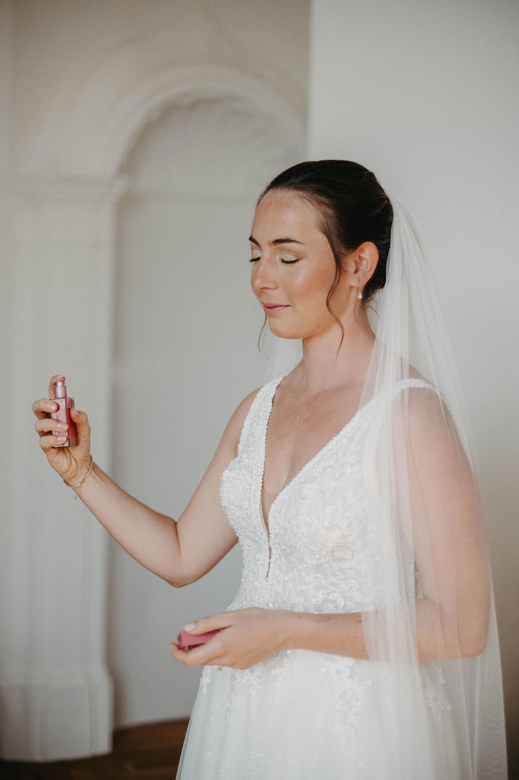 A bride in a white lace wedding dress and veil poses with closed eyes in a series of elegant portraits.