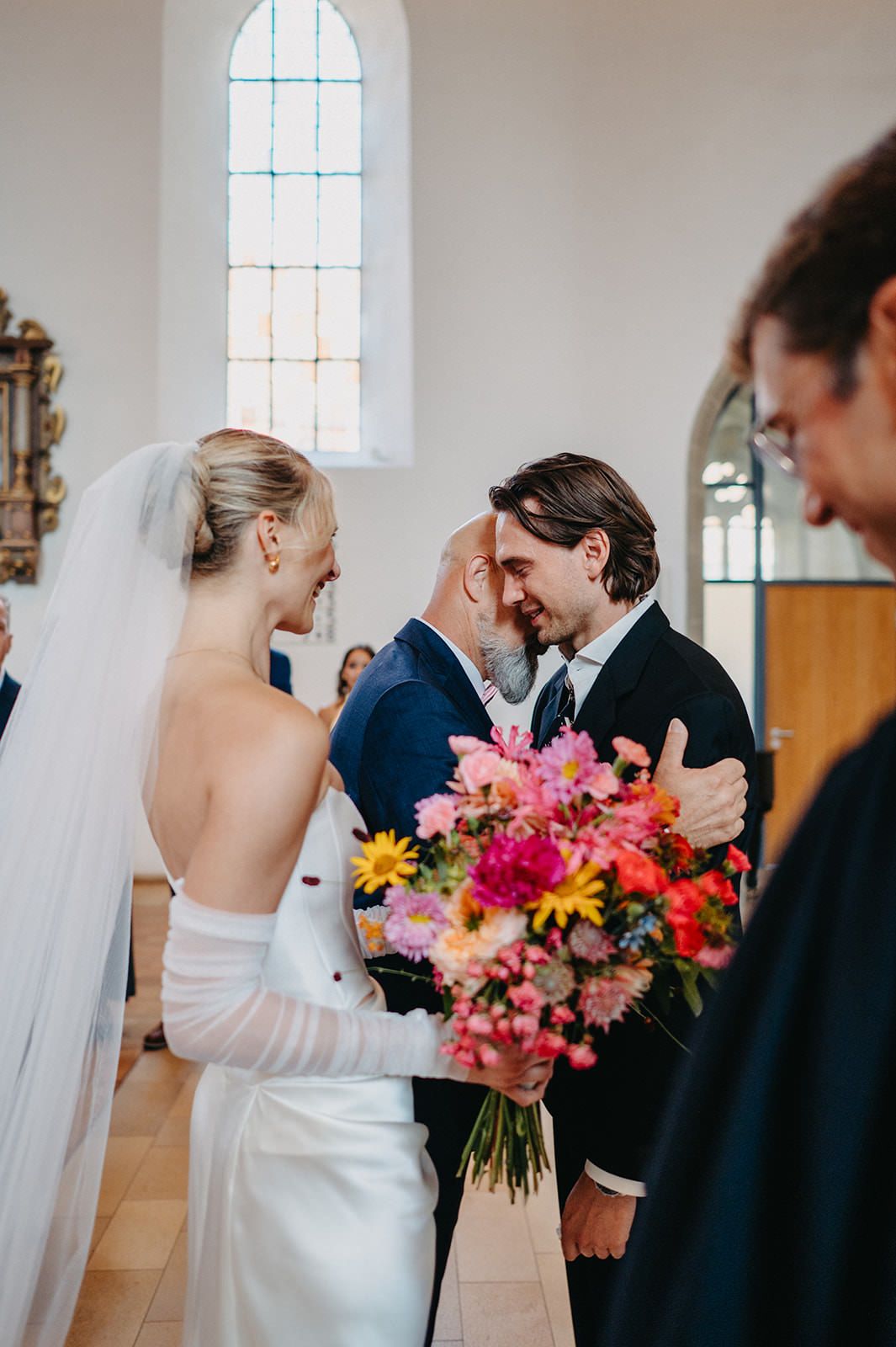 A series of wedding photos showing couples sharing intimate moments with vibrant floral bouquets in a church setting.