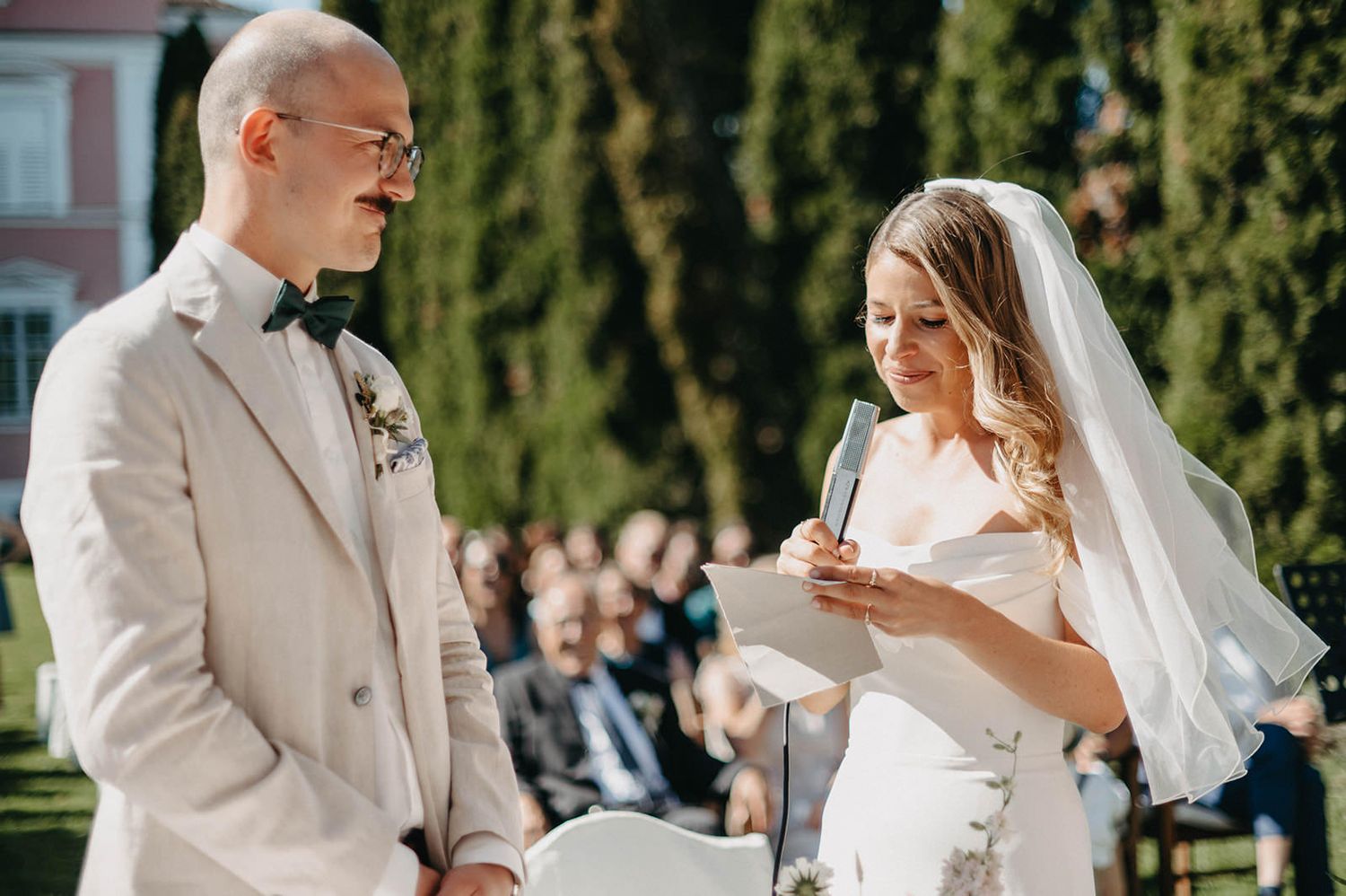 A couple shares a joyful moment during their outdoor wedding ceremony on a sunny day.