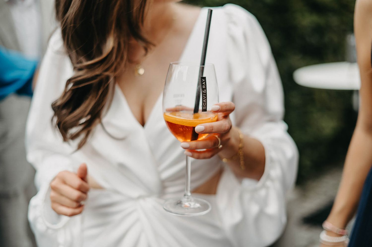 Wedding celebration with guests holding colorful cocktails during an outdoor reception.