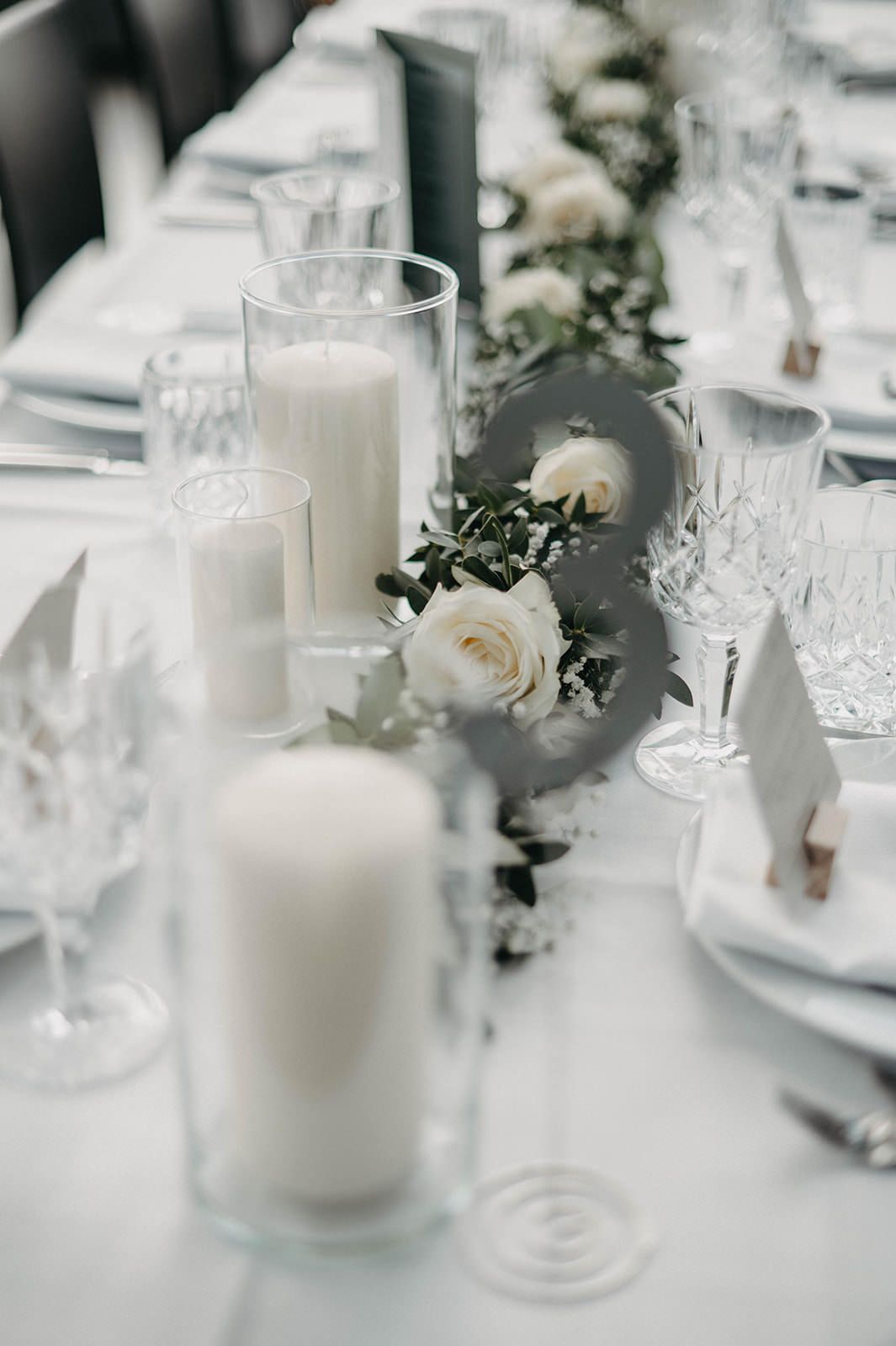 Elegant white candles and roses create a romantic table setting with delicate butterfly decorations and crystal glassware.