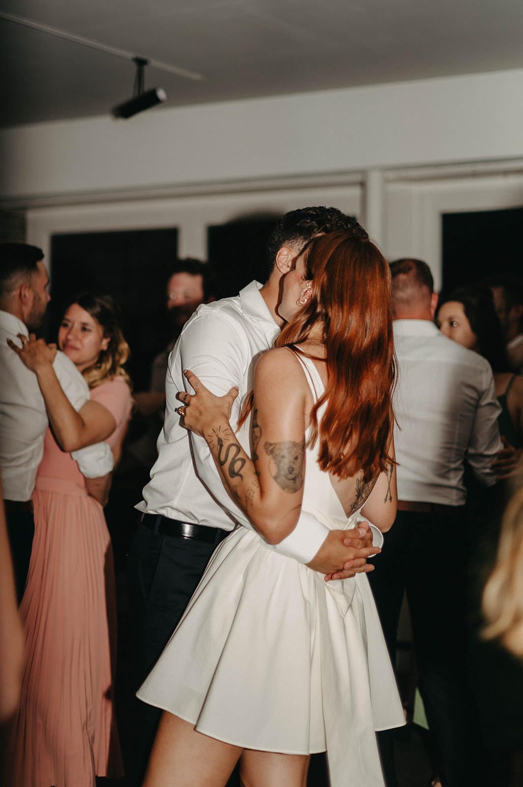 Wedding reception guests dance together on the dance floor during an evening celebration.