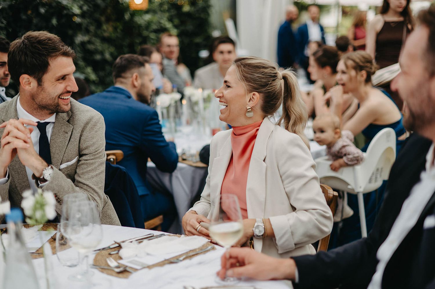 Wedding guests gathered at elegant reception tables share joyful moments during dinner celebration.
