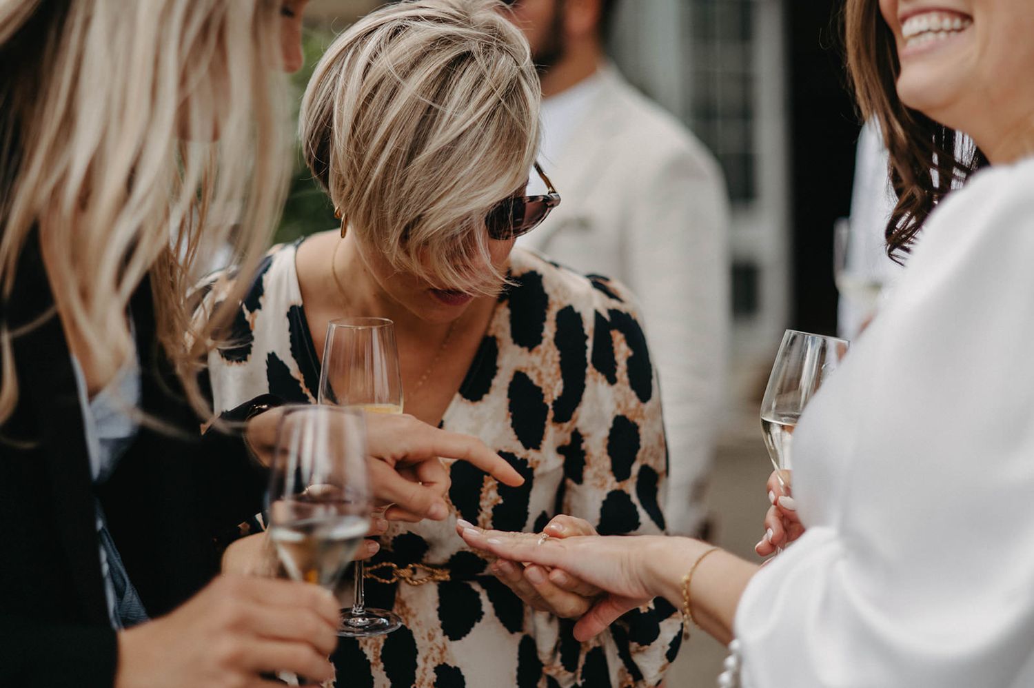 Group of friends enjoying champagne at a social gathering wearing stylish outfits including a leopard print top.