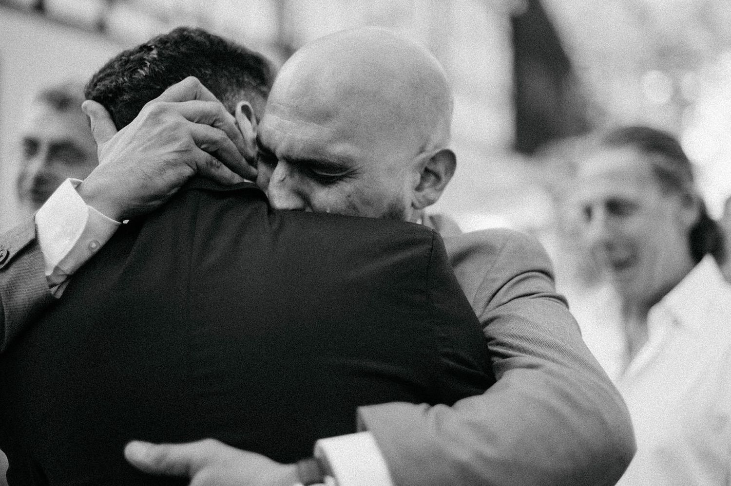 A black and white photo montage shows five emotional embraces between people at what appears to be a wedding celebration.