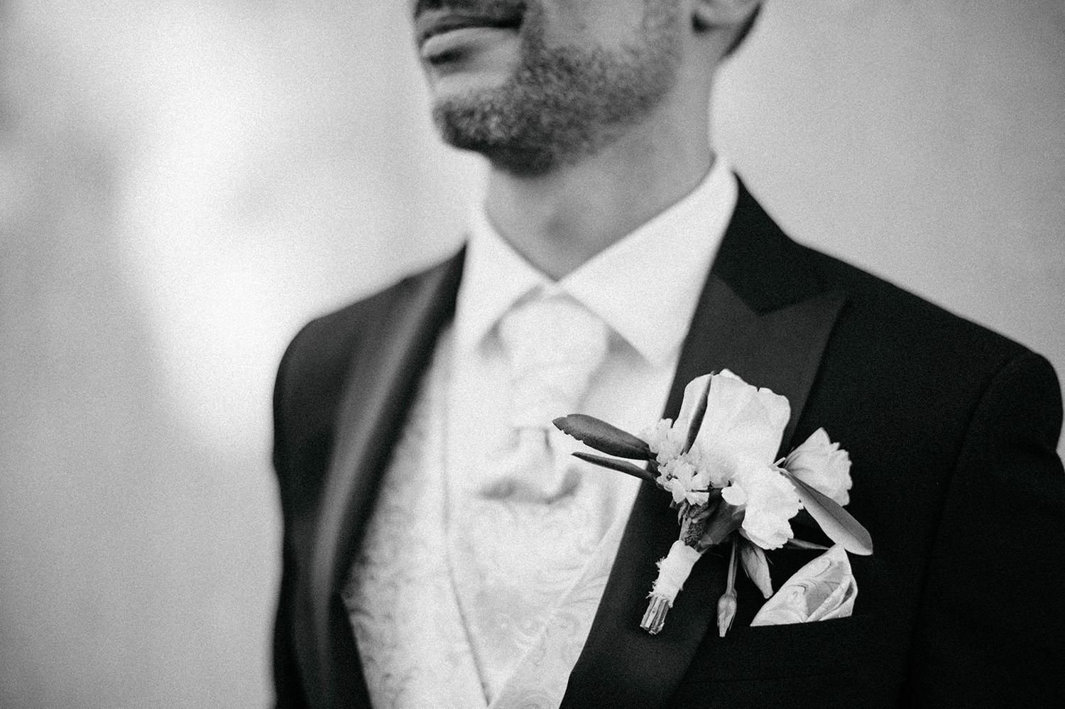 A black and white collage of formal wedding attire details showing boutonnieres, ties, and suit jackets.