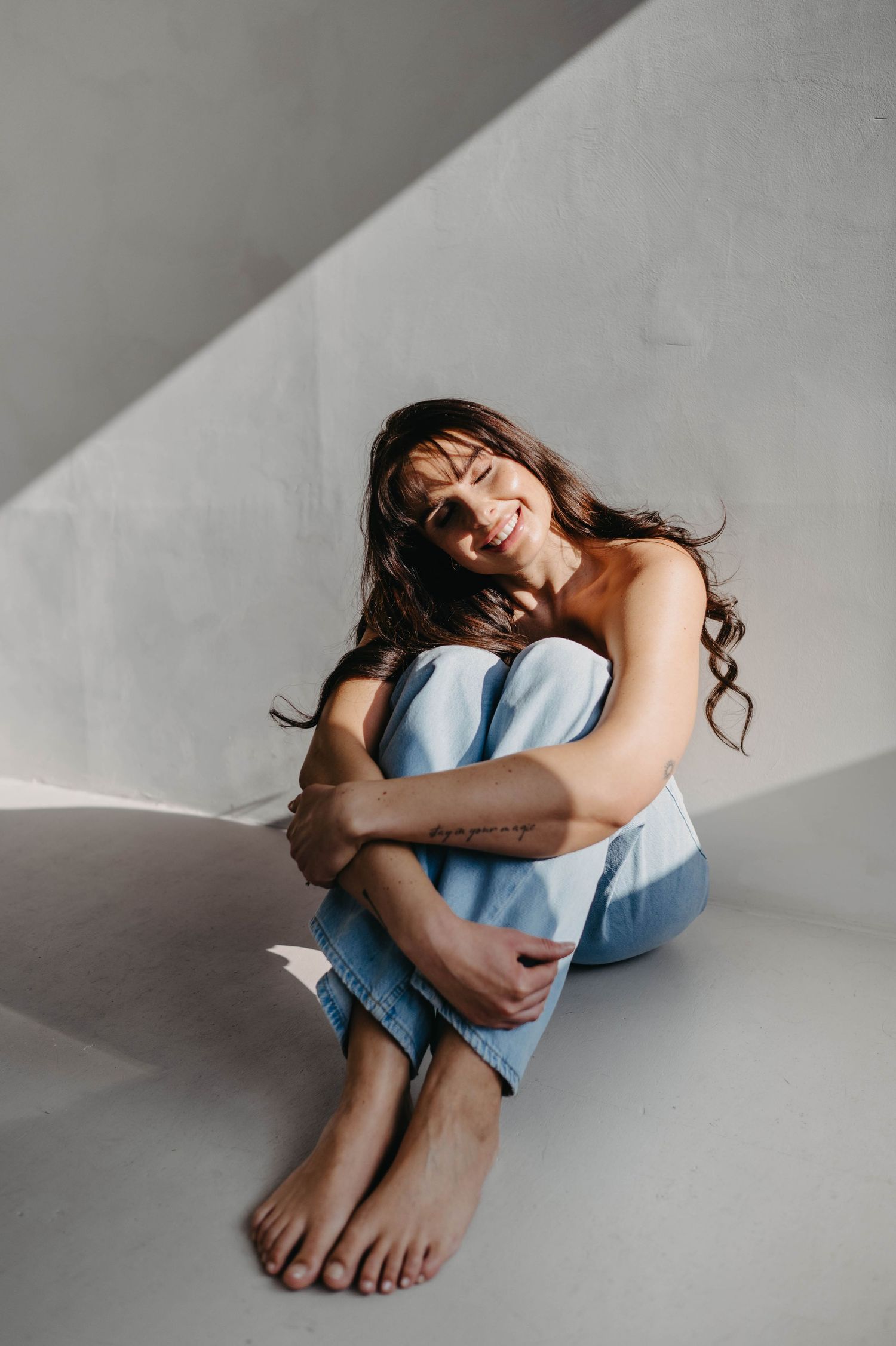 Minimalist portrait in light blue clothing with natural poses on white floor.