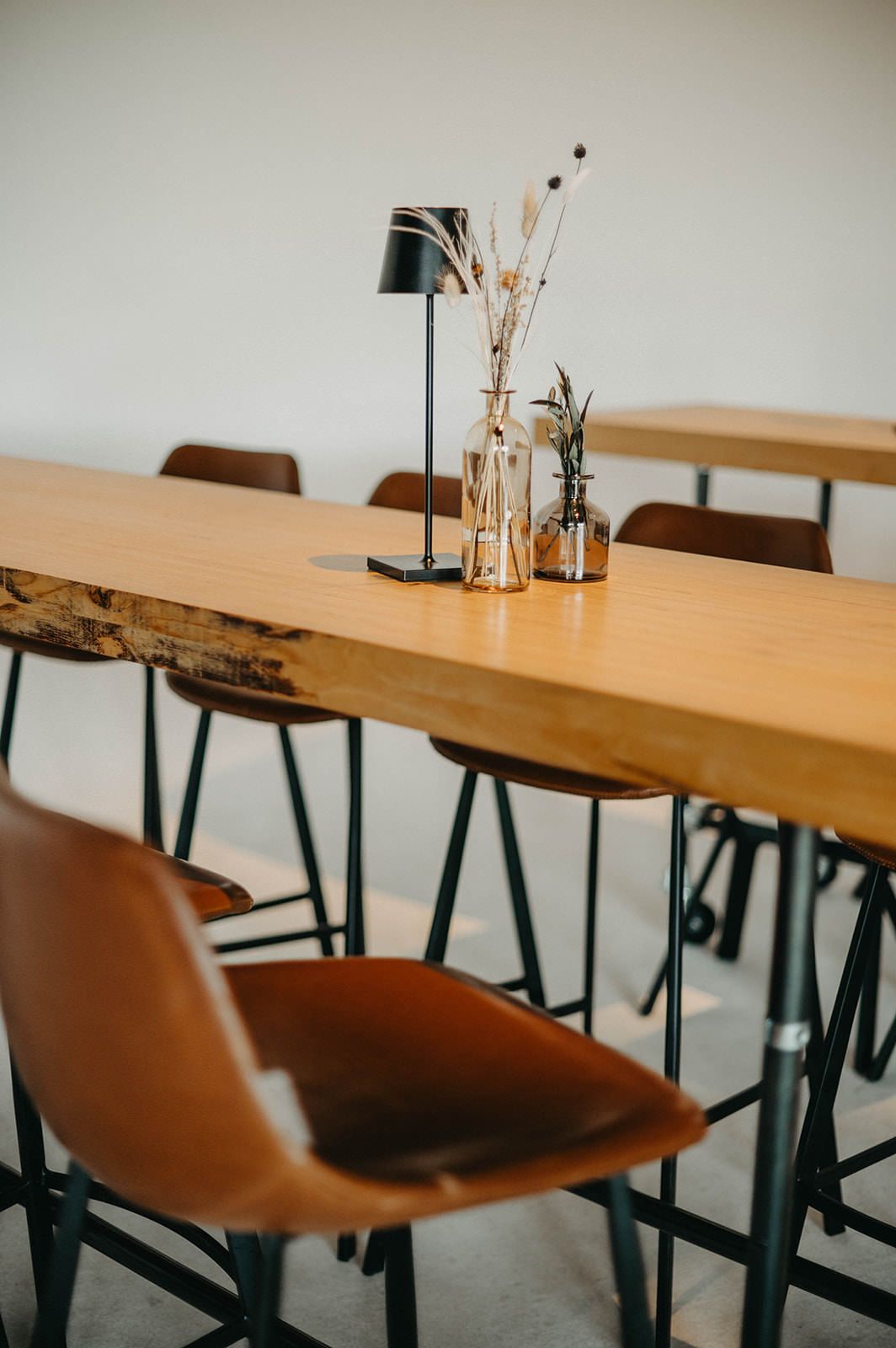Modern dining room featuring a live edge wooden table with brown leather chairs and minimalist decor.