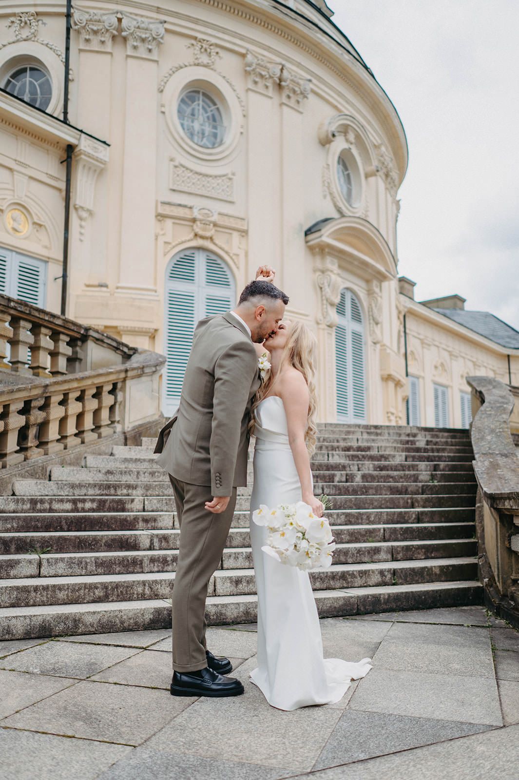 A sequence of photos showing a couple in wedding attire sharing a romantic moment on grand stone steps of an elegant building.