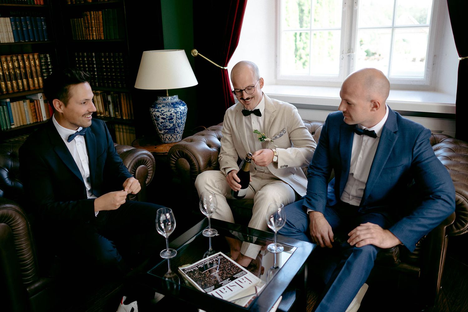 Guests engage in conversation while relaxing in a wood-paneled library or study setting.