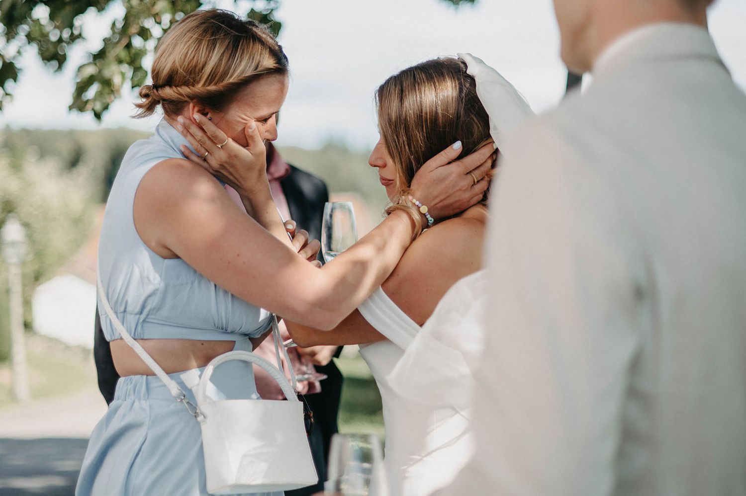 Emotional wedding moment captured between bride and groom embracing outdoors in natural lighting.