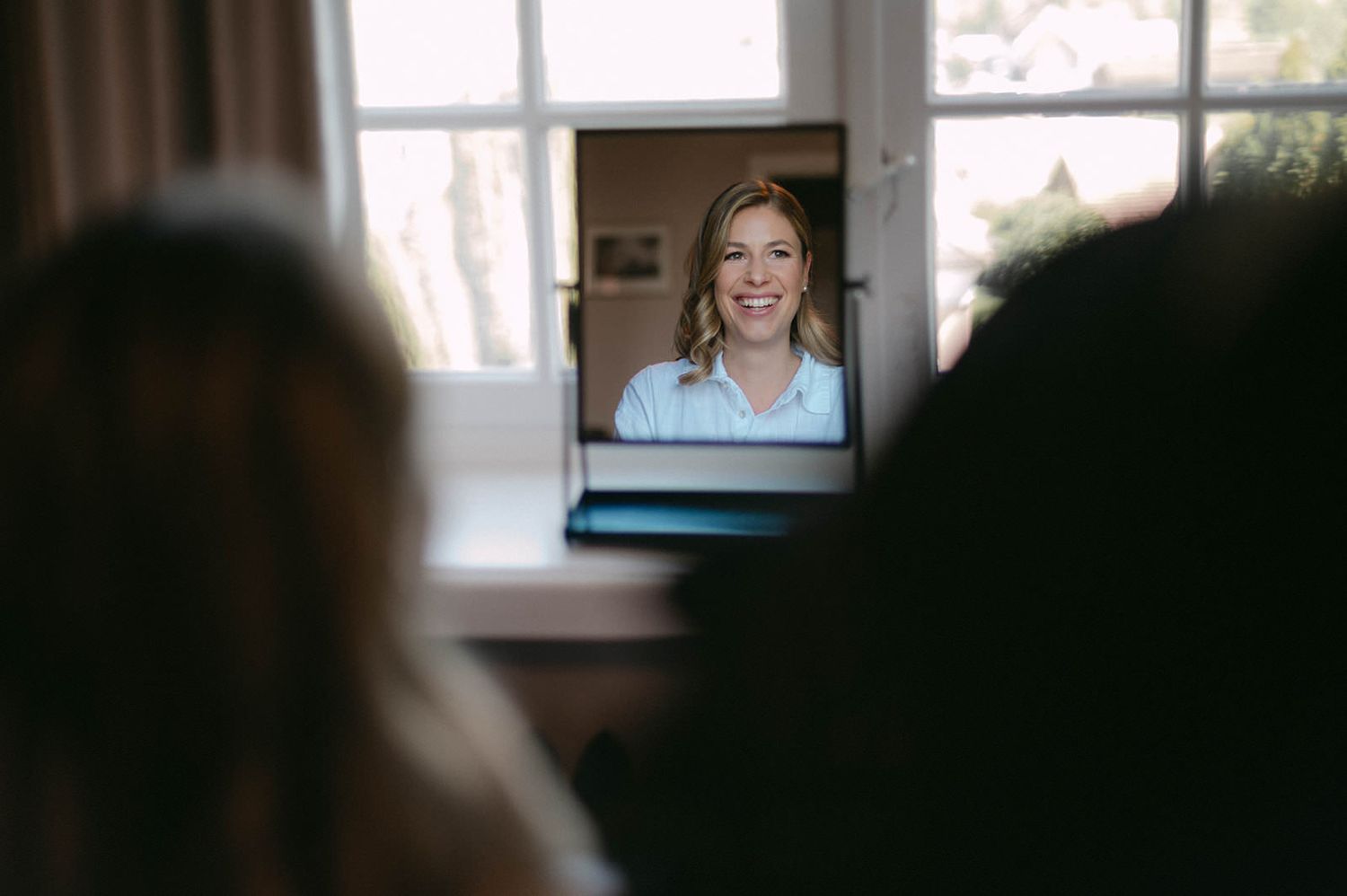 A person is seen in a video chat window on a laptop screen in a bright room.