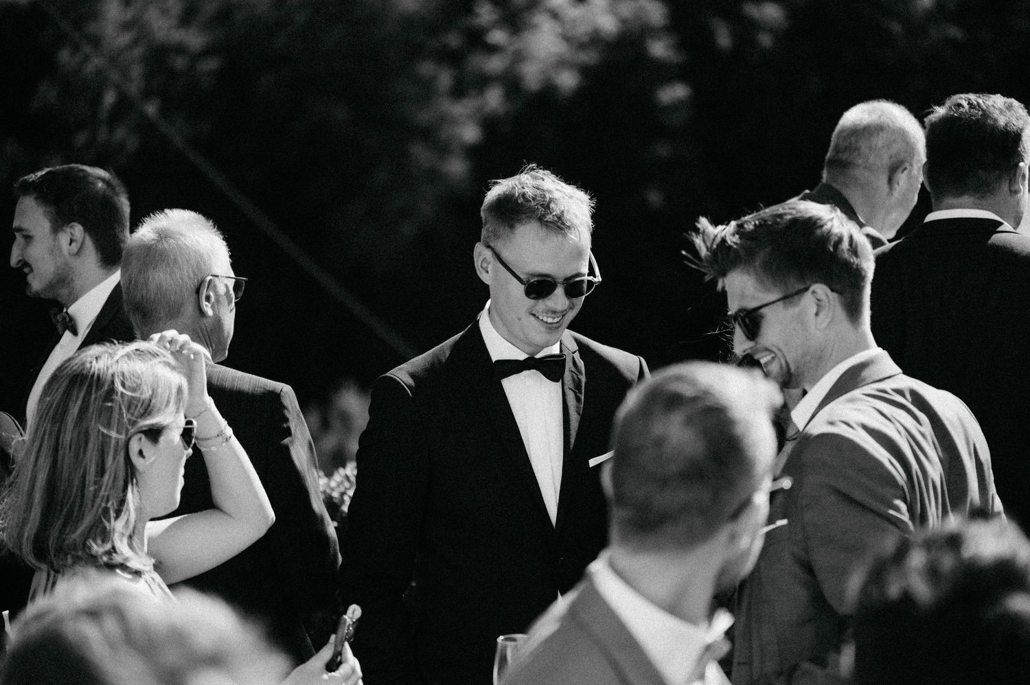 Stylish wedding guests mingle during outdoor reception in black and white.