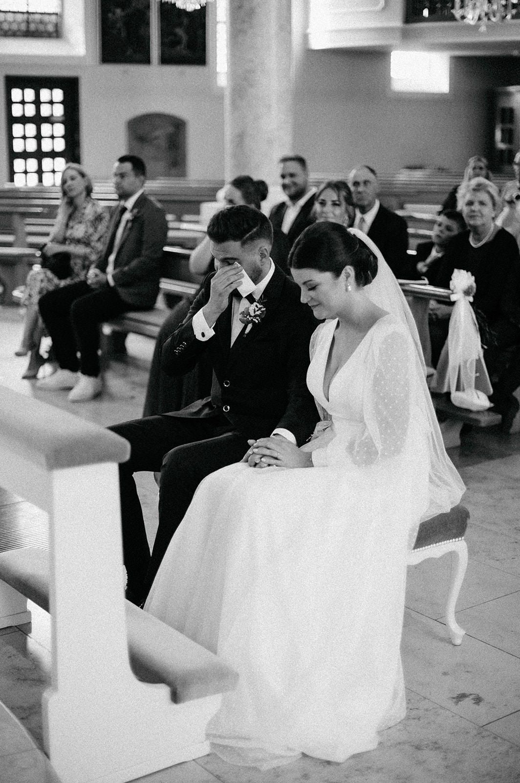 A series of black and white wedding ceremony photos showing a couple seated in a church pew during their special day.