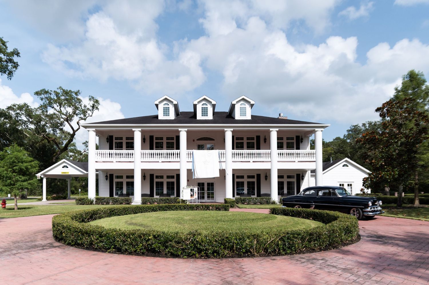 Elegant white Southern plantation-style venue with columns, balconies, and circular driveway.