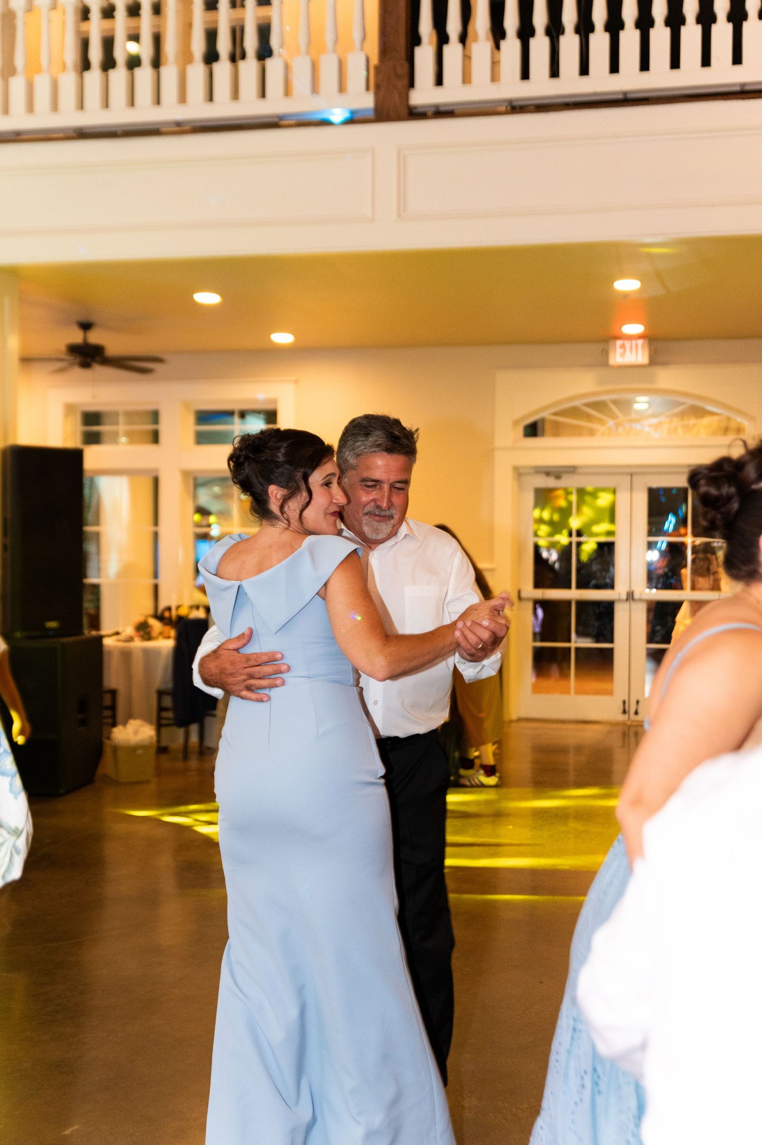 Couple shares romantic dance under warm lights at elegant wedding reception venue.