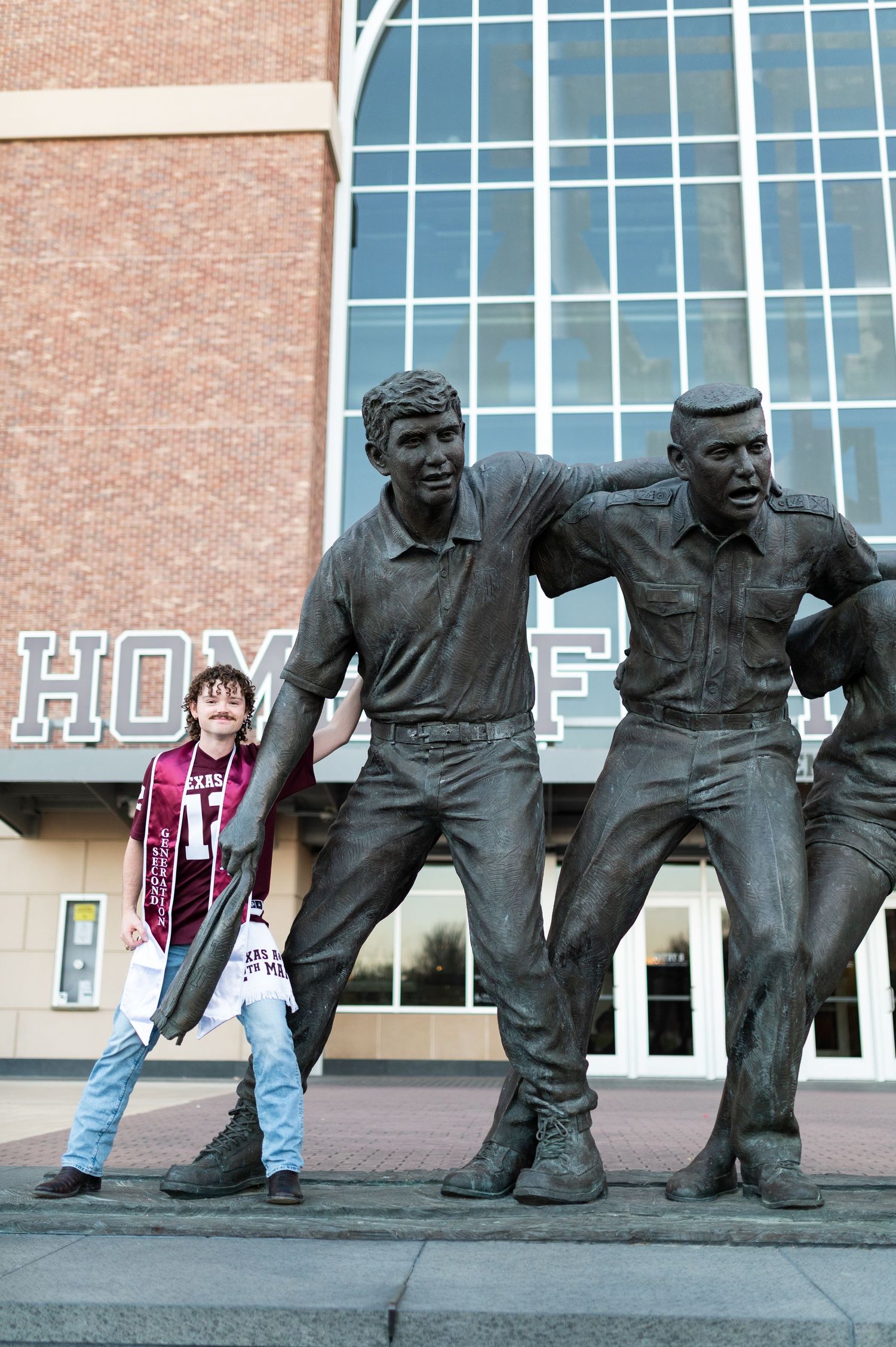 Texas A&M fan poses with bronze statues outside the Home of the 12th Man stadium in College Station.