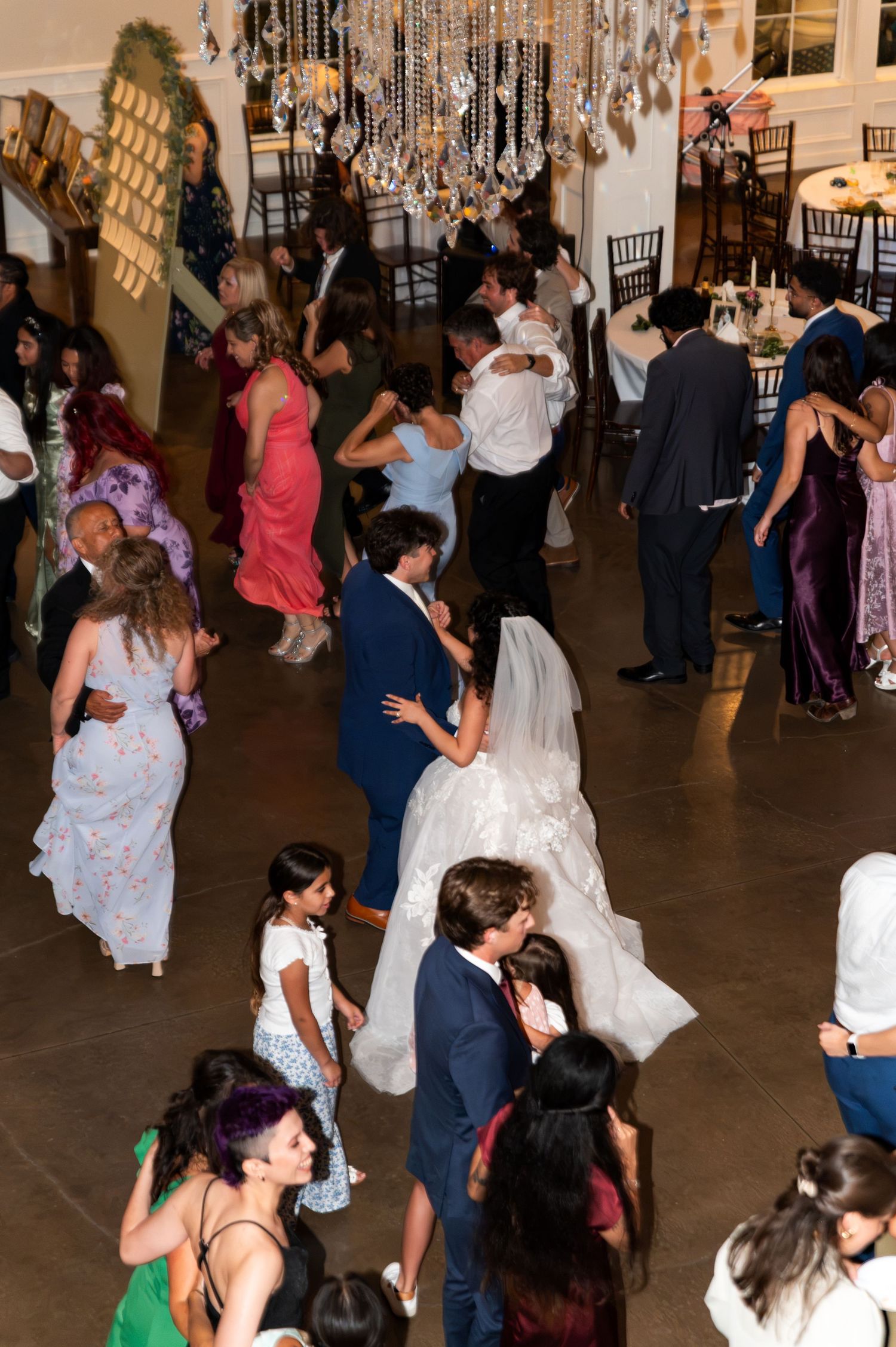 Overhead view of bride groom and guests filling the dance floor at lively wedding reception.