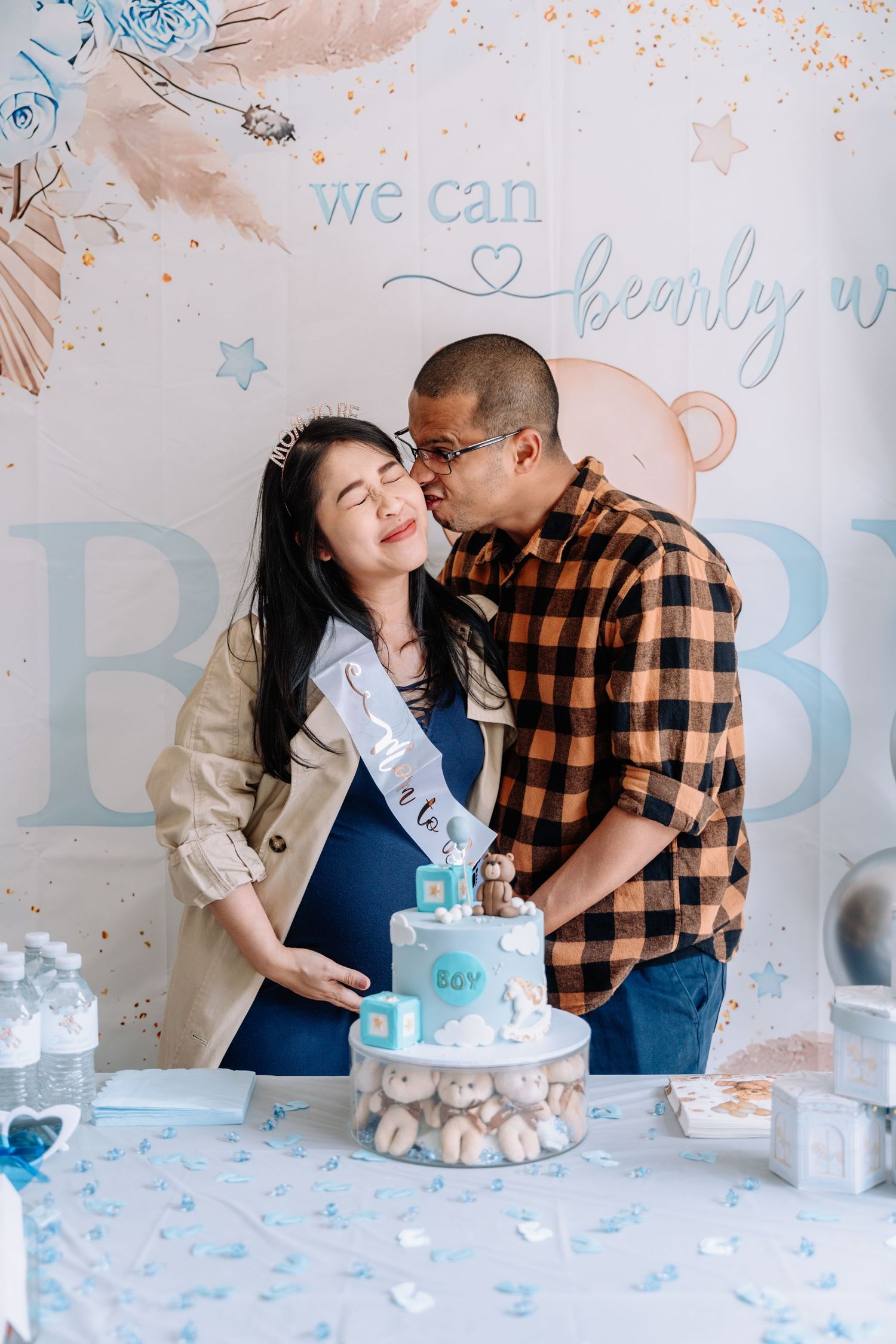 A couple sharing tender moments while celebrating with a blue and white decorated cake.