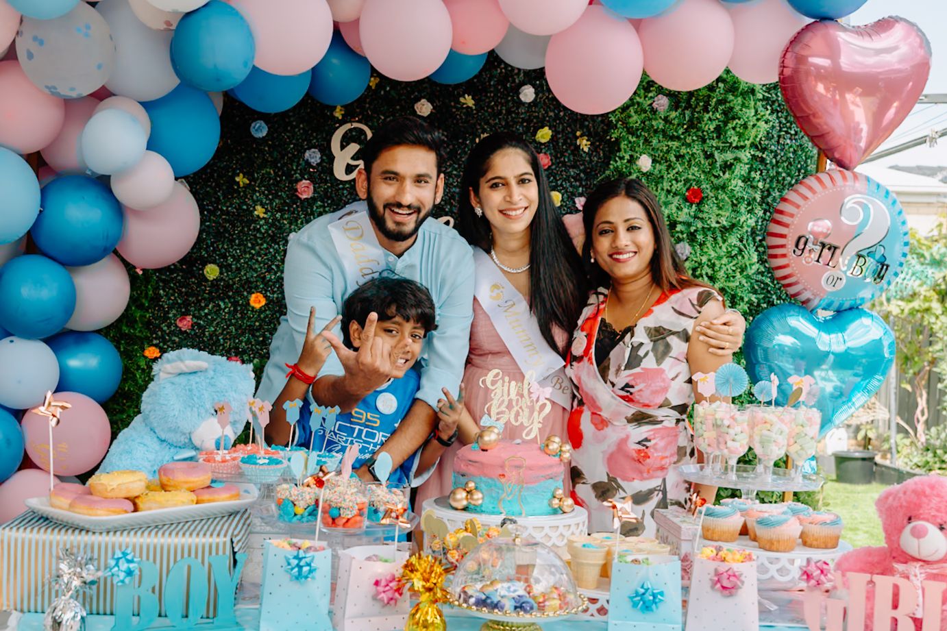 Pink and blue balloon arch decorating a party space with dessert table setup.