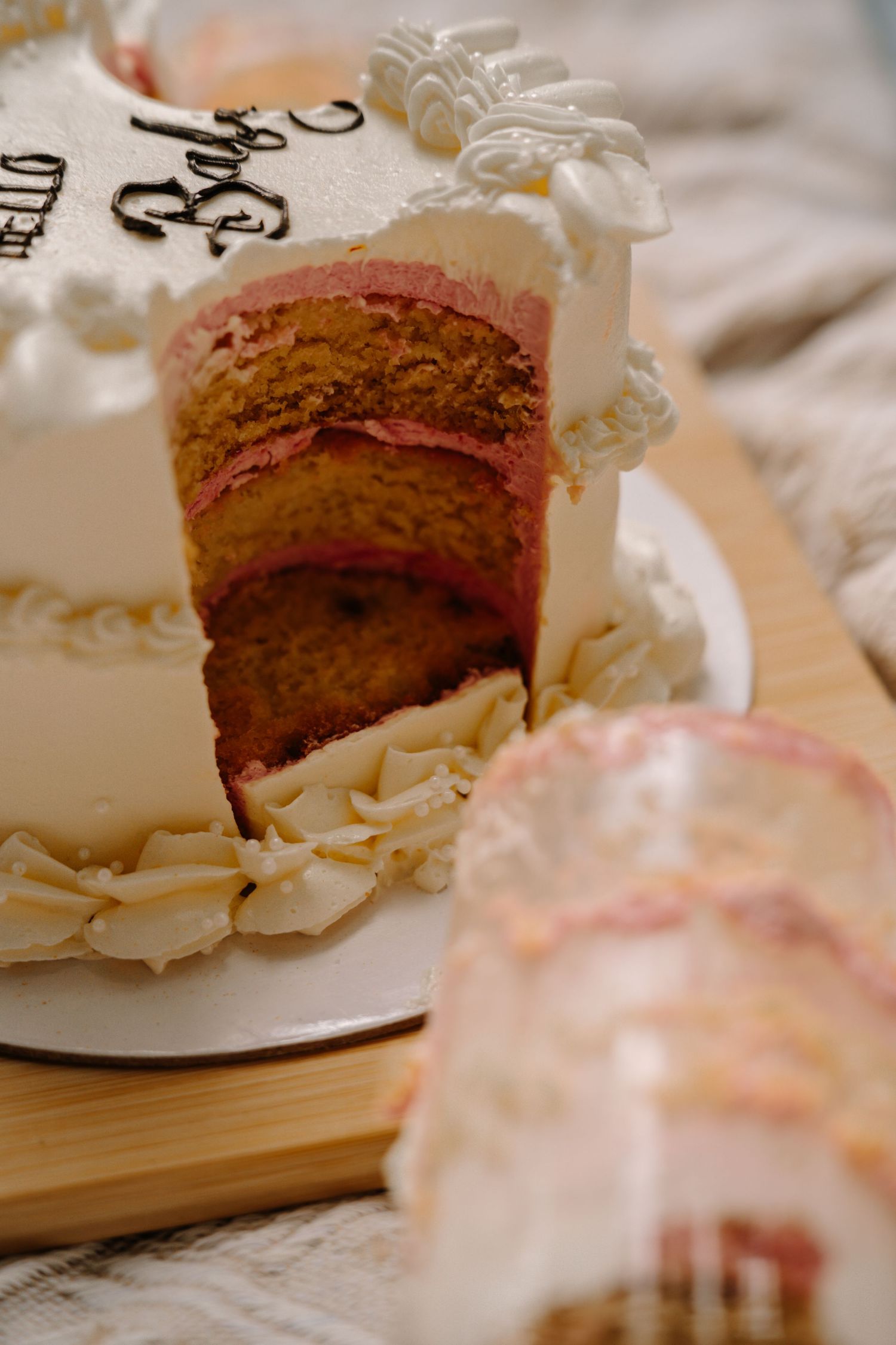 Close-up of a sliced wedding cake showing layers of pink and golden sponge with white frosting.
