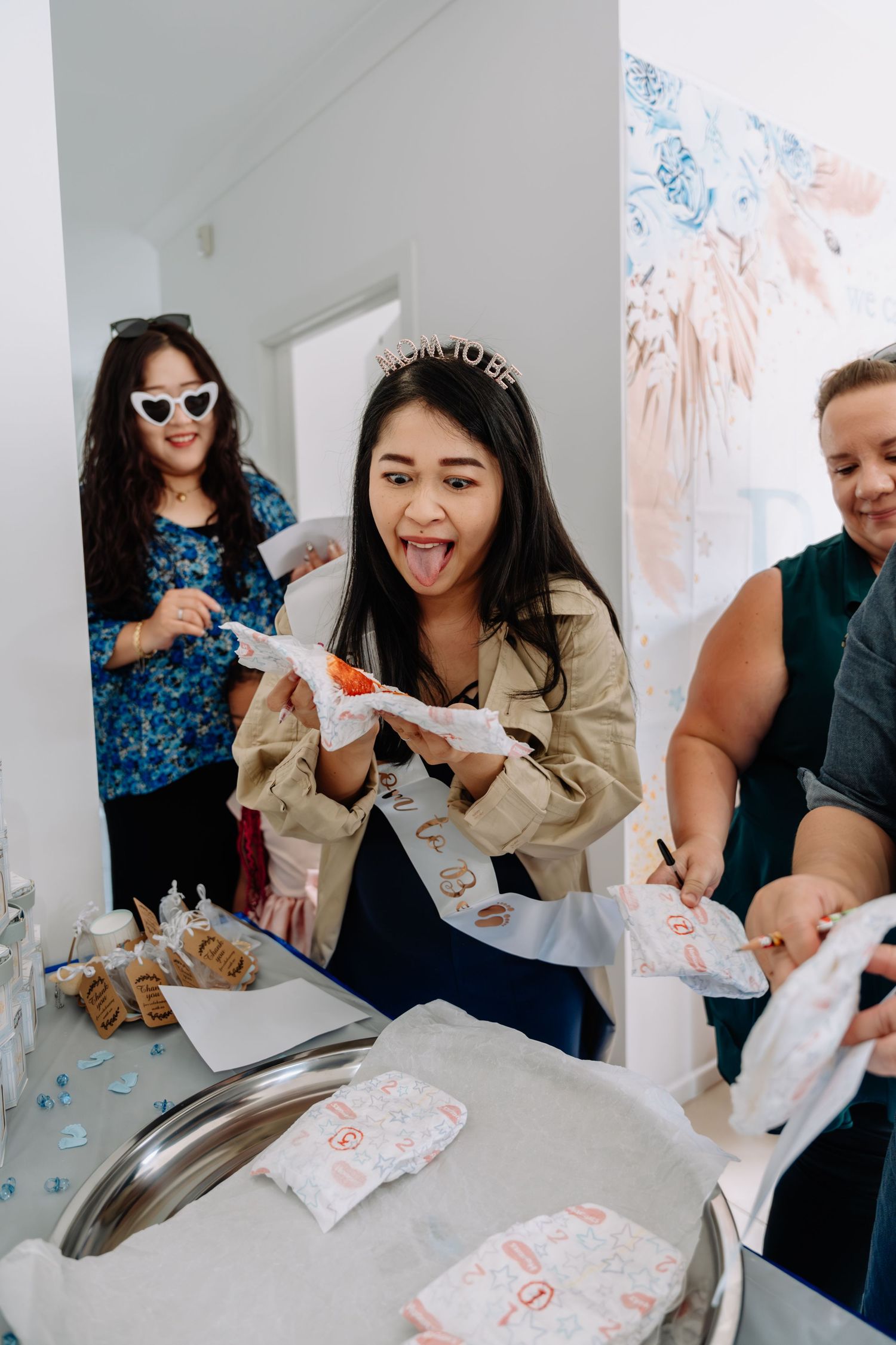 People enjoying snacks and treats at a festive celebration with decorative wall art.