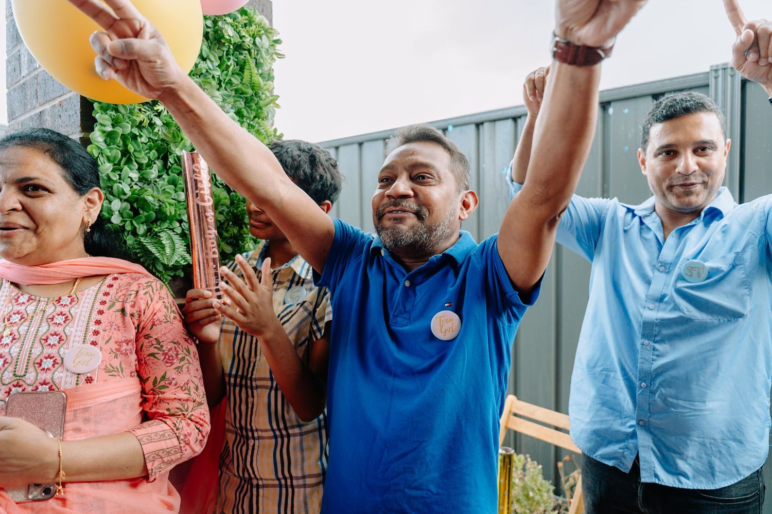 Group of people celebrating at an outdoor party with raised hands and joyful expressions.