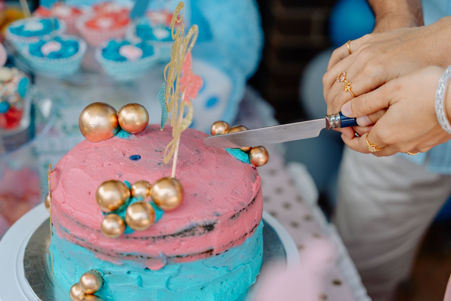 Pink cake decorated with gold accents and metallic decorations for a celebration.