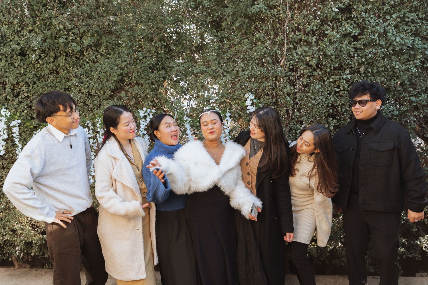 A group of friends laughing and having fun together outdoors while wearing winter coats.