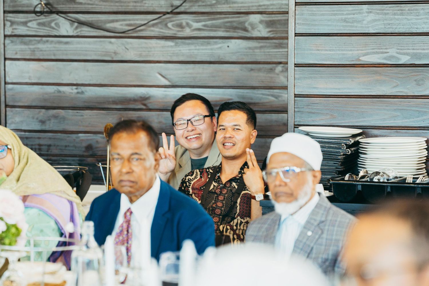 Wedding guests smile and pose for photos at a rustic wooden reception venue.