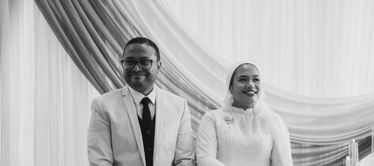 Black and white portrait of smiling bride and groom at elegant wedding ceremony.