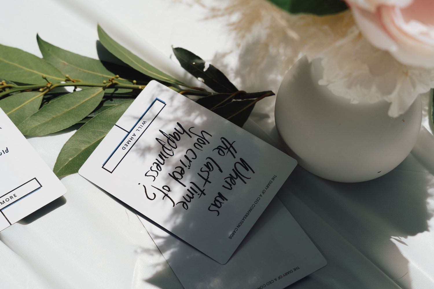 Wedding invitation suite with handwritten calligraphy, white roses, and green foliage on a light background.