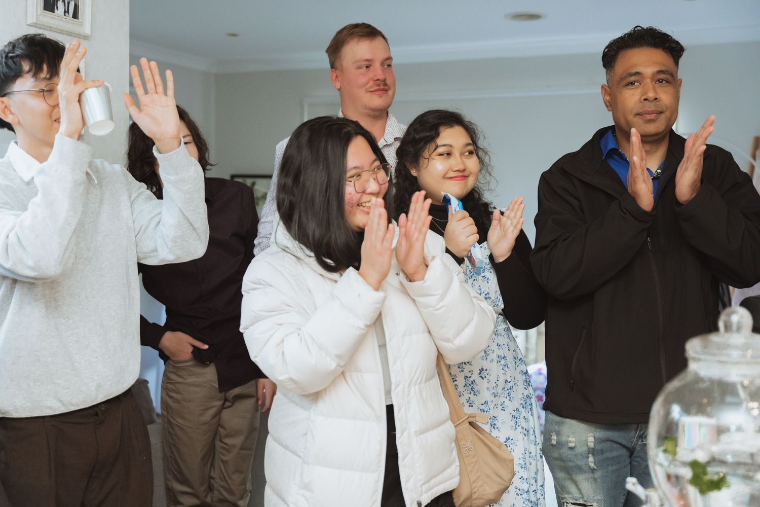 Group of wedding guests clapping and celebrating during a festive indoor reception.