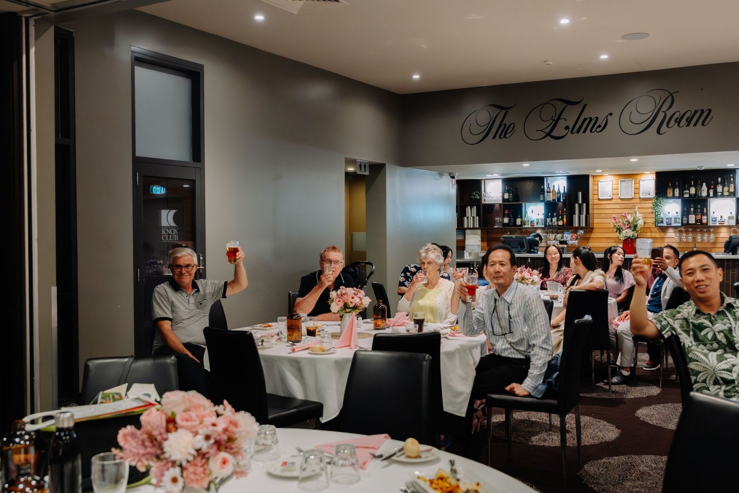 Wedding reception guests seated at decorated tables in The Lilac Room restaurant with pink floral centerpieces.