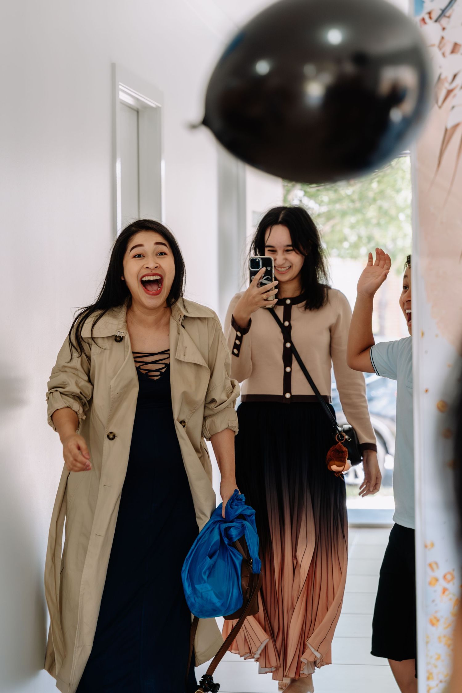 Friends having fun at a party with black balloons and casual outfits in a bright indoor setting.