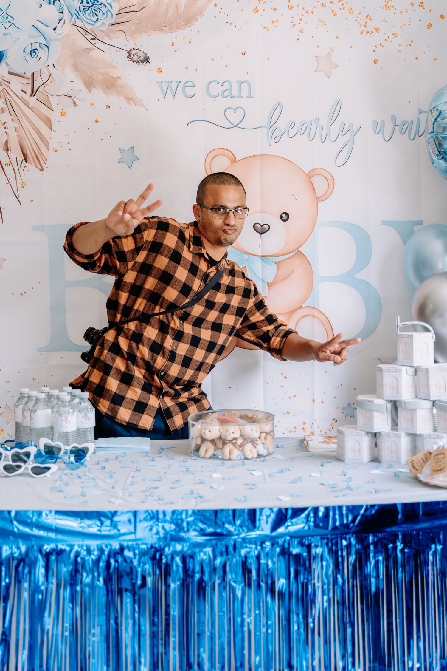 A party setup with blue metallic fringe backdrop and white decorative elements against a wall with pastel accents.