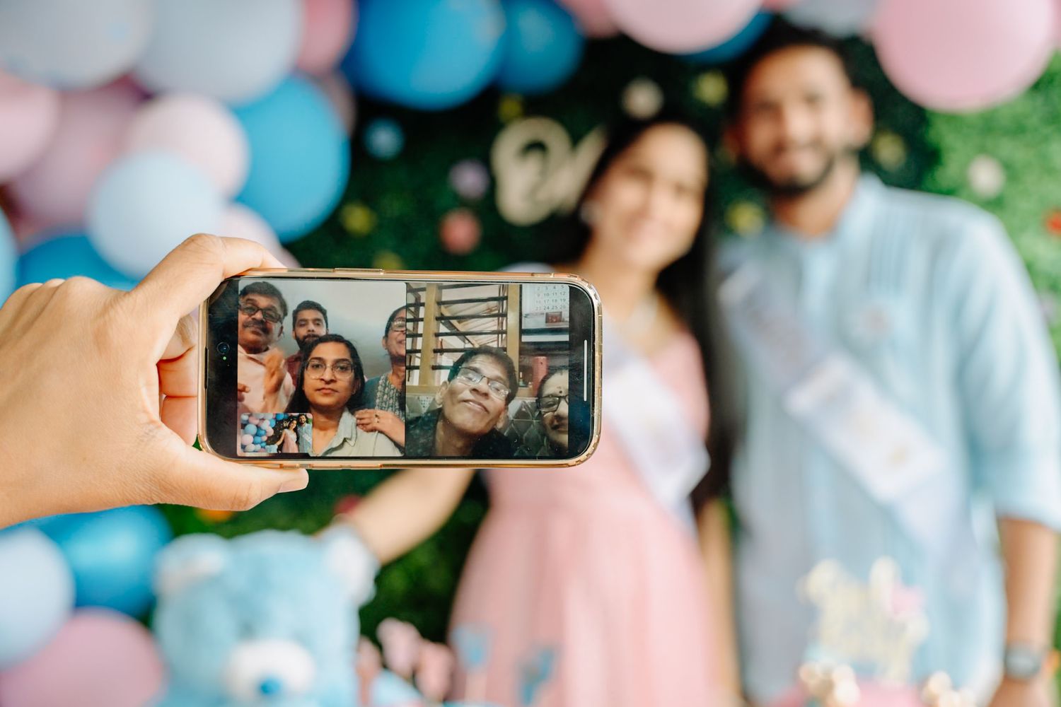 Group of people celebrating at a gender reveal party with blue and pink decorations.