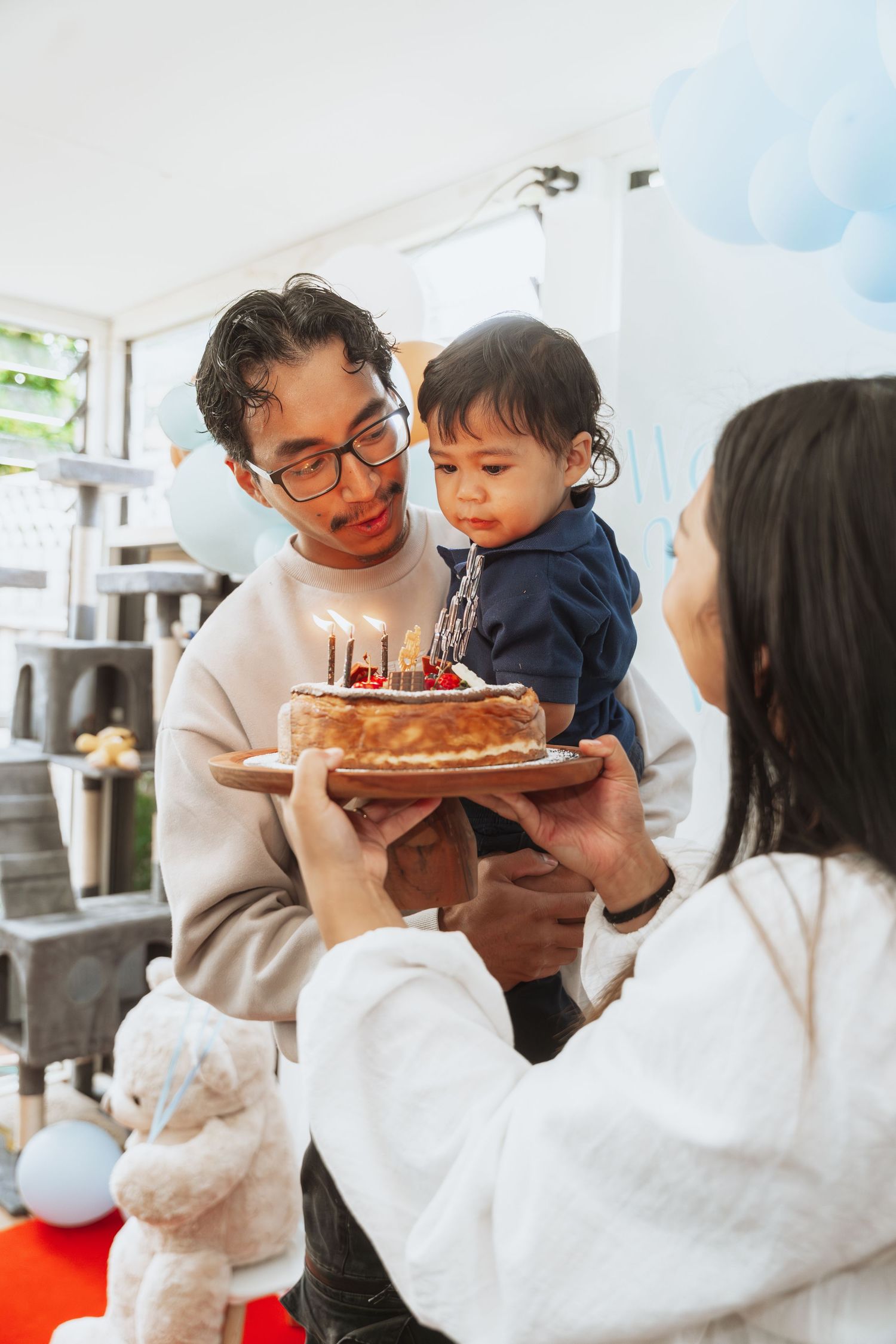 Family celebrating birthday with cake as toddler helps blow out candles in series of candid moments.