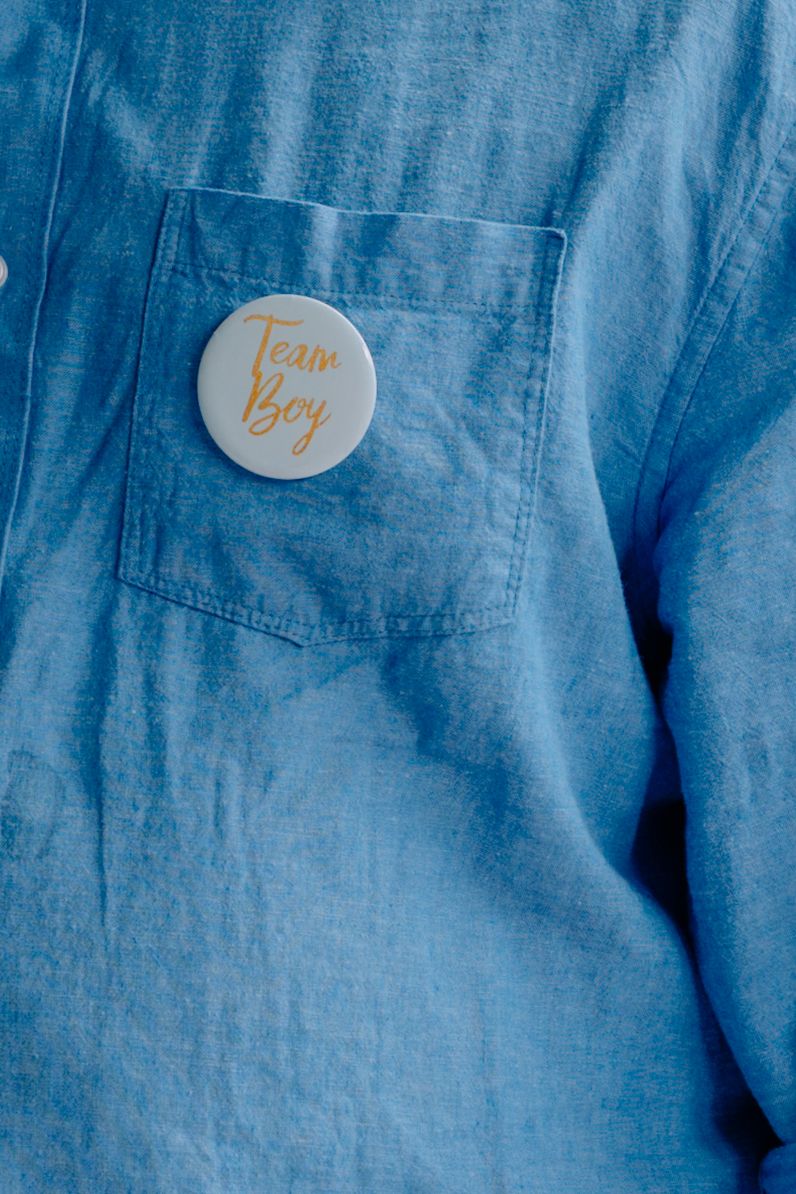 Close-up view of denim fabric with small round gold-colored pins or badges arranged in a row.