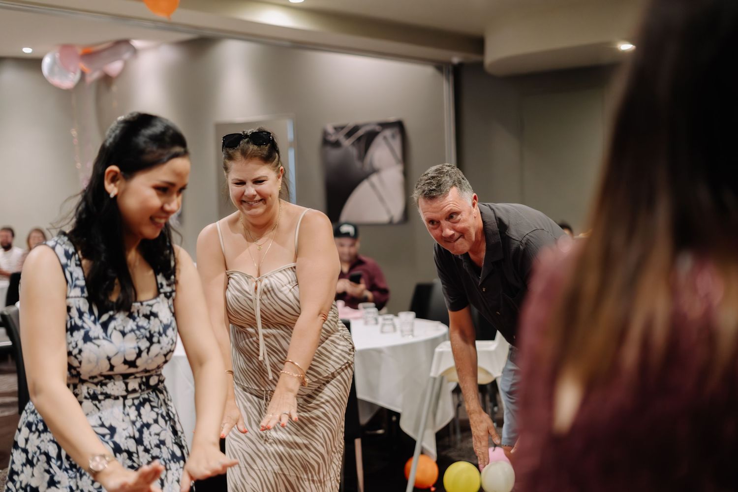 A group of people share a candid moment of laughter during a reception in an elegant indoor venue.