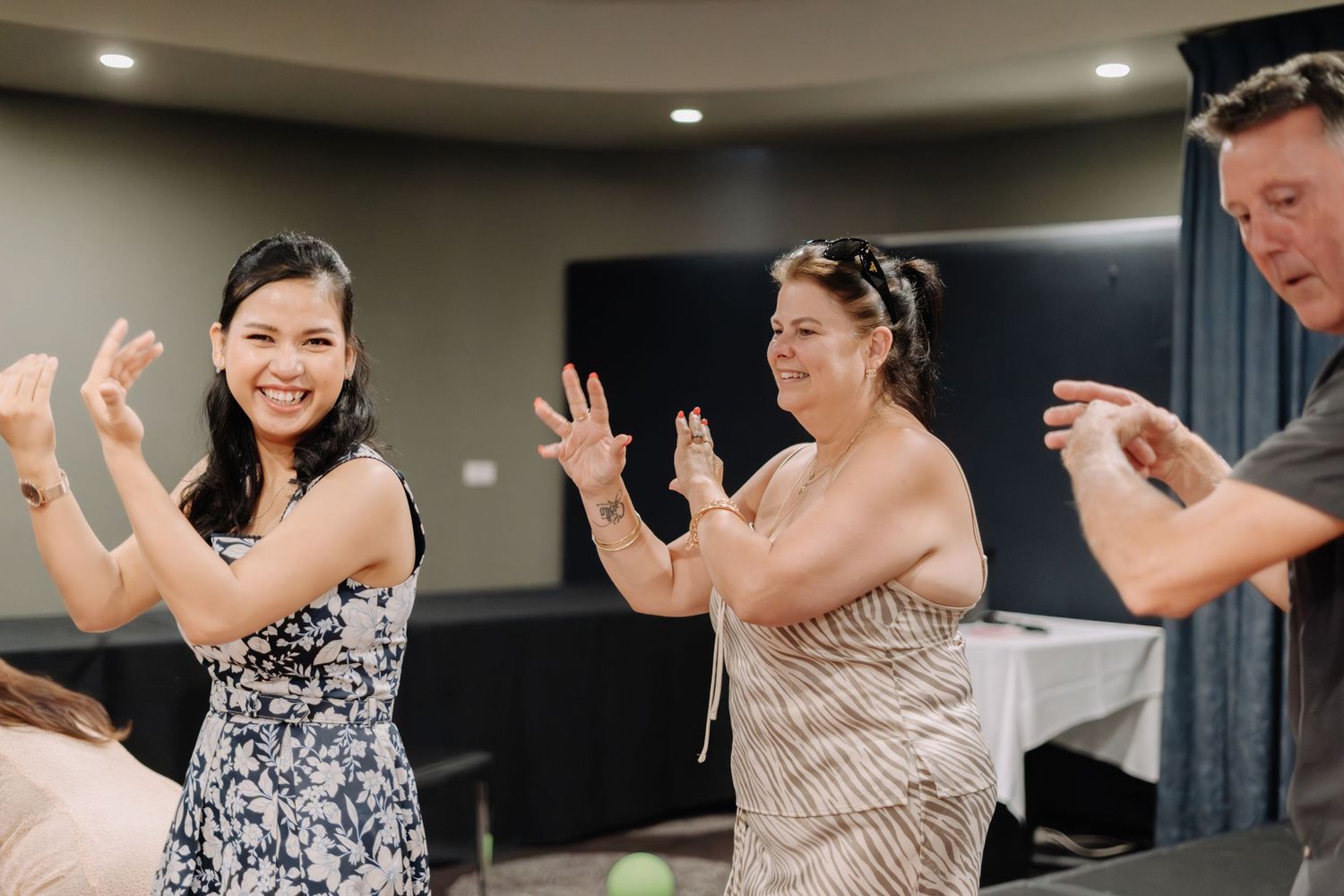 People dancing together in a group formation at an indoor event with recessed lighting.