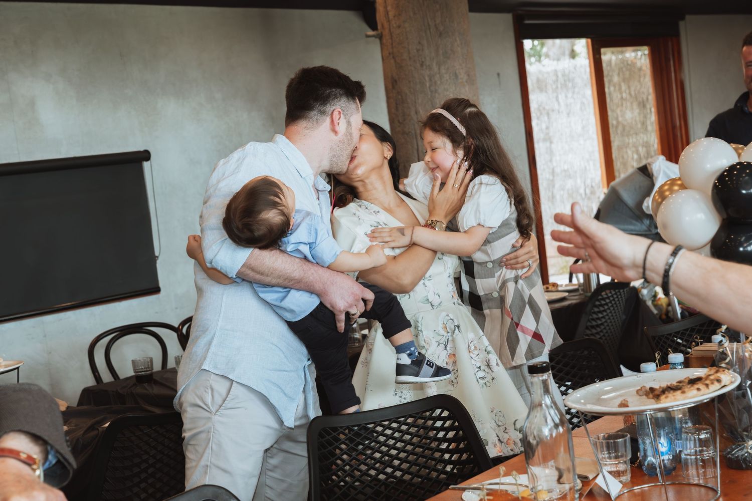 An intimate family gathering at a restaurant with people embracing and sharing a special moment together.
